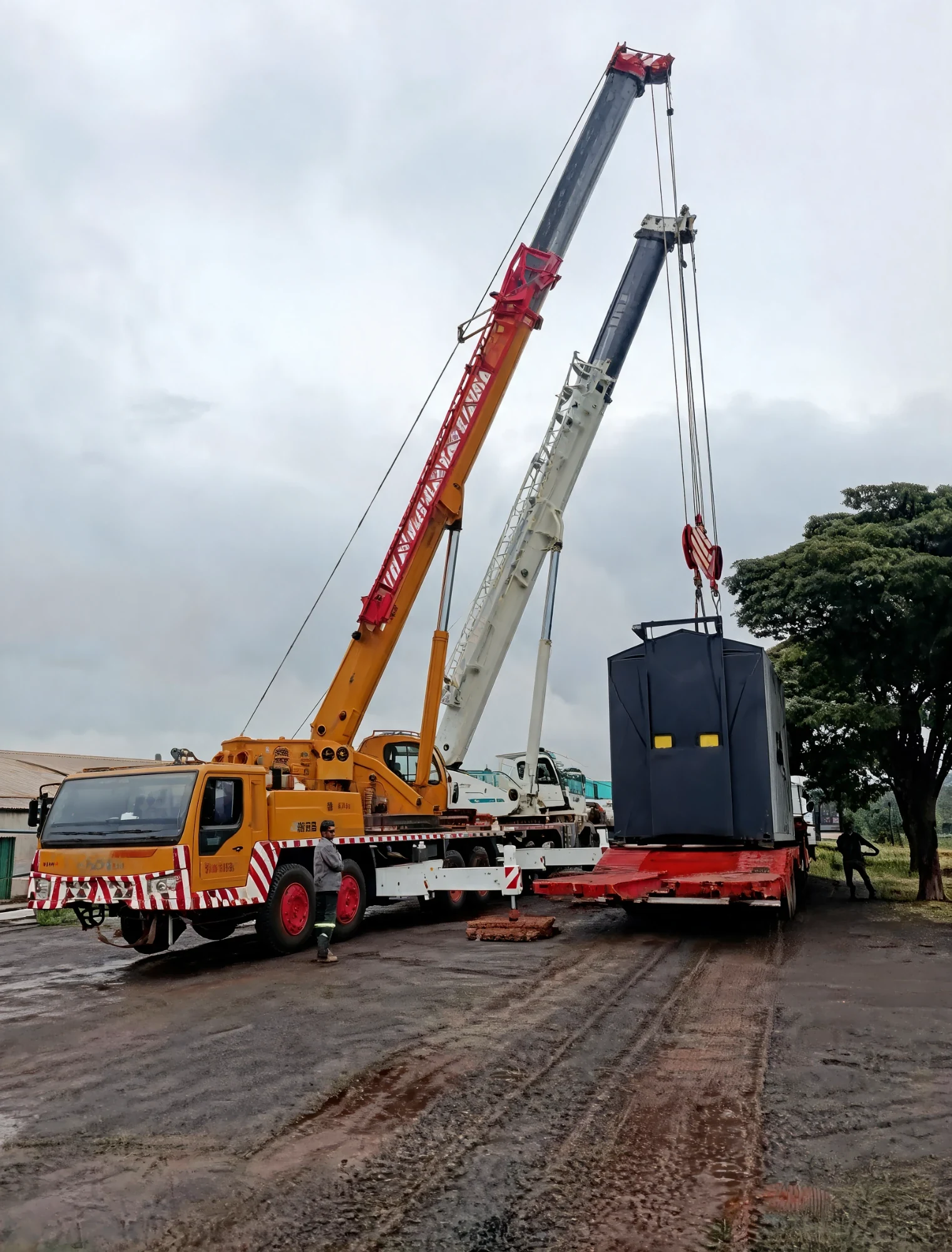 Guindaste rodoviário içando um equipamento industrial para cima de uma carreta